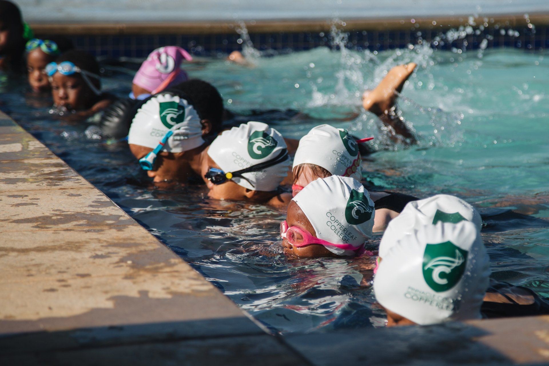 A group of children are swimming in a swimming pool.