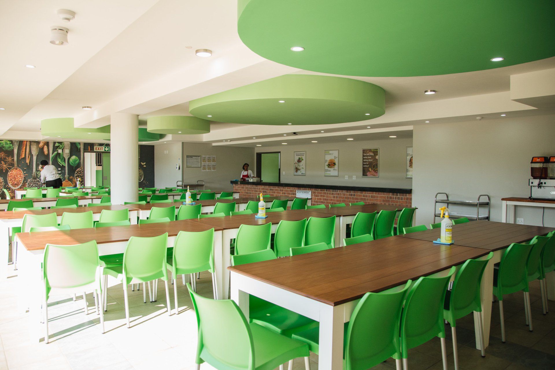 A large dining room with green chairs and tables.