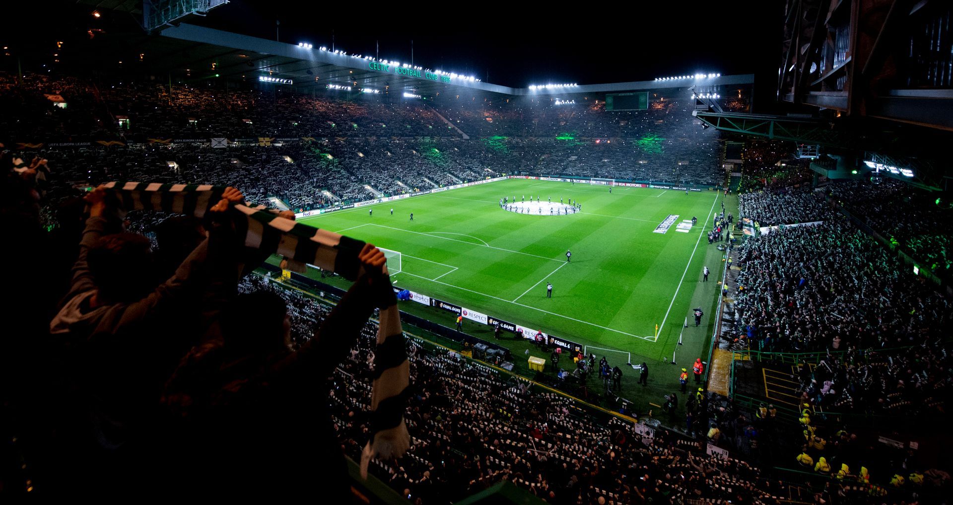 A crowd of people are watching a soccer game in a stadium at night.