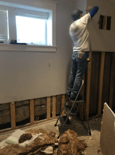 A man is standing on a ladder in a room.