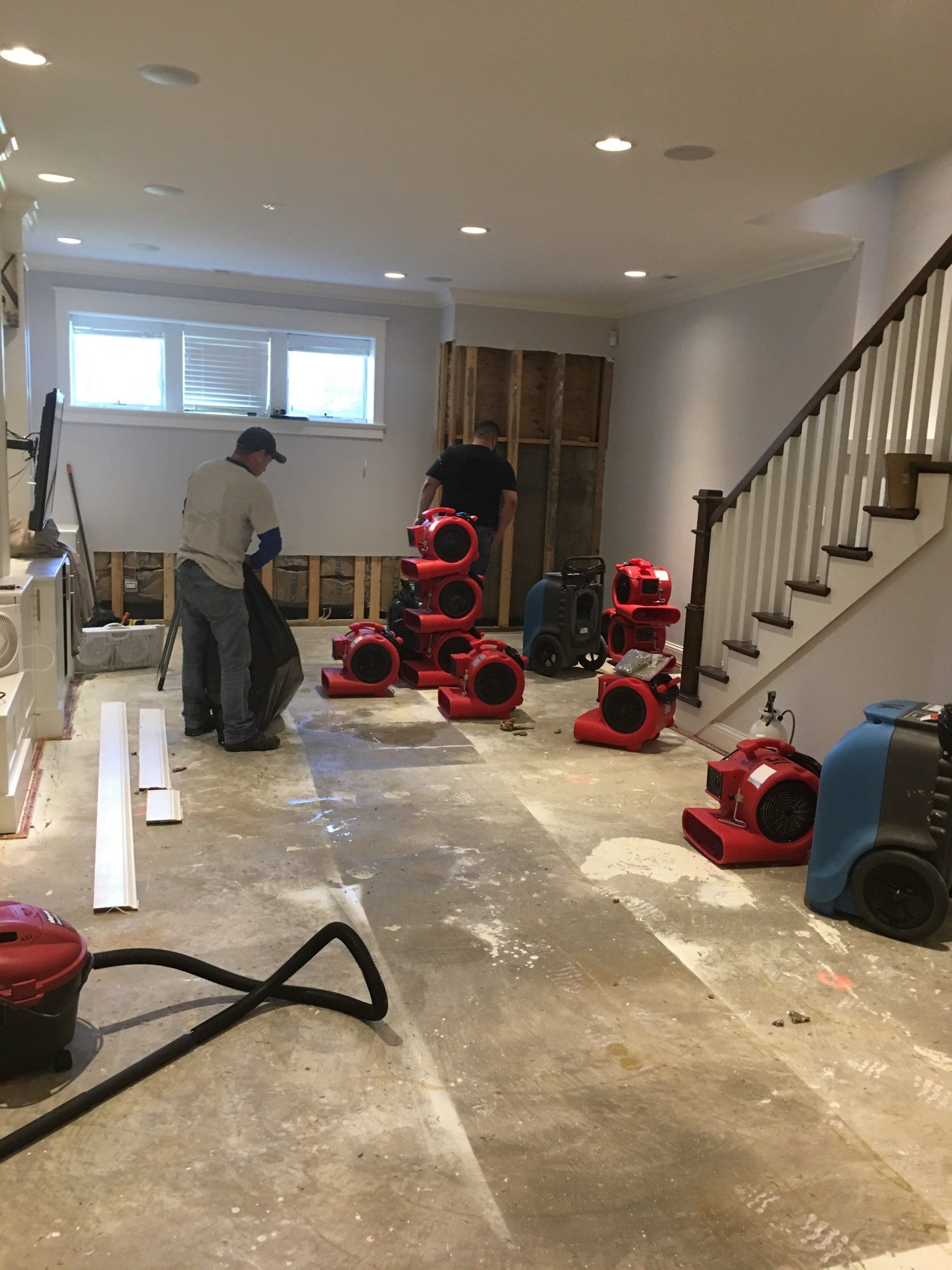 A man is standing in a basement with a vacuum cleaner.