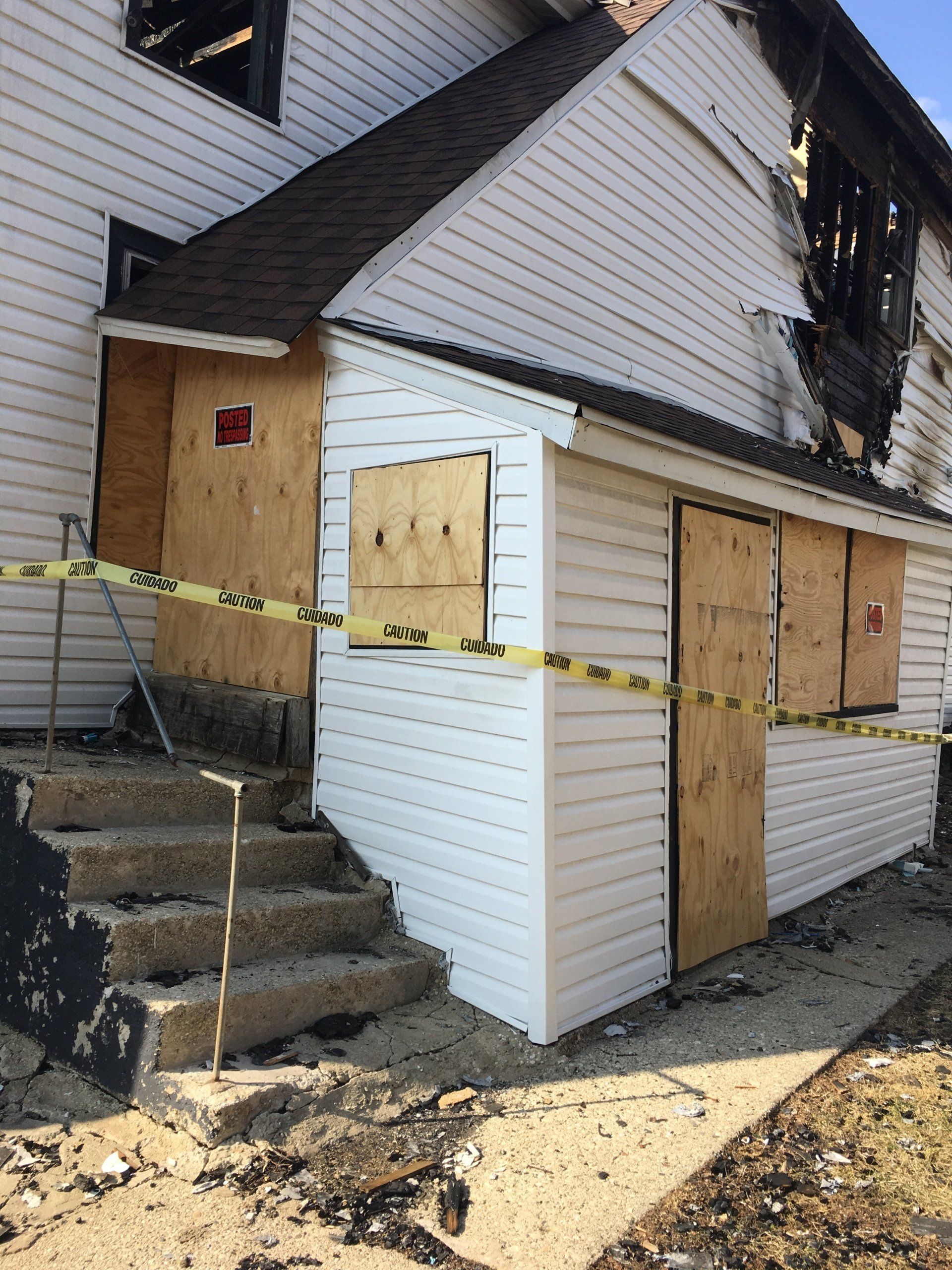 A house that has been damaged by a fire and is boarded up.