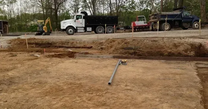 A dump truck is driving down a dirt road next to a construction site.
