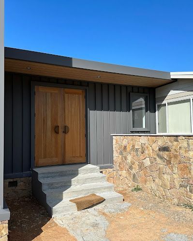 A house with a wooden door and stairs leading up to it. — Thomas Croker Constructions In Myrtleville, NSW