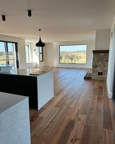 A large empty room with hardwood floors and a fireplace. — Thomas Croker Constructions In Myrtleville, NSW