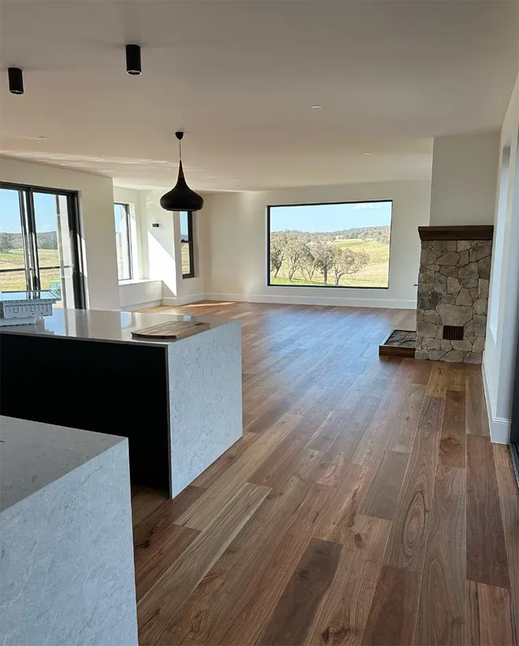 A large empty room with hardwood floors and a fireplace. — Thomas Croker Constructions In Myrtleville, NSW