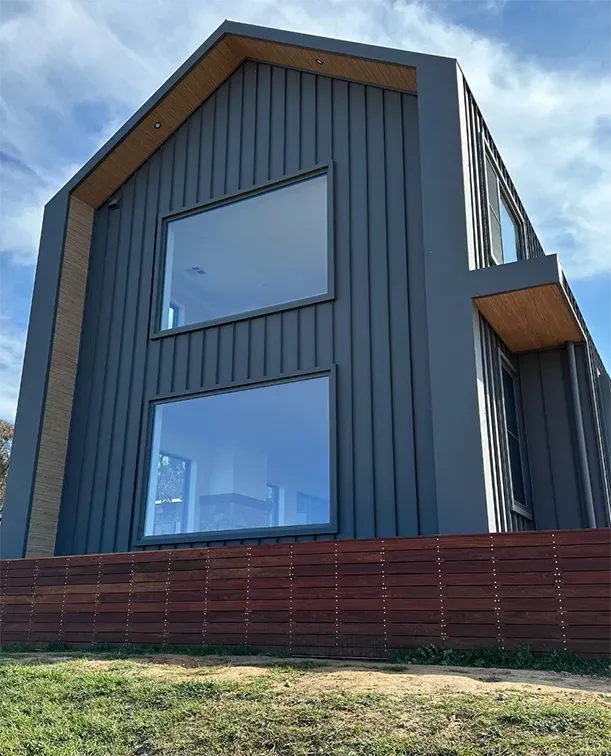 A large house with a lot of windows and a wooden fence in front of it. — Thomas Croker Constructions In Myrtleville, NSW