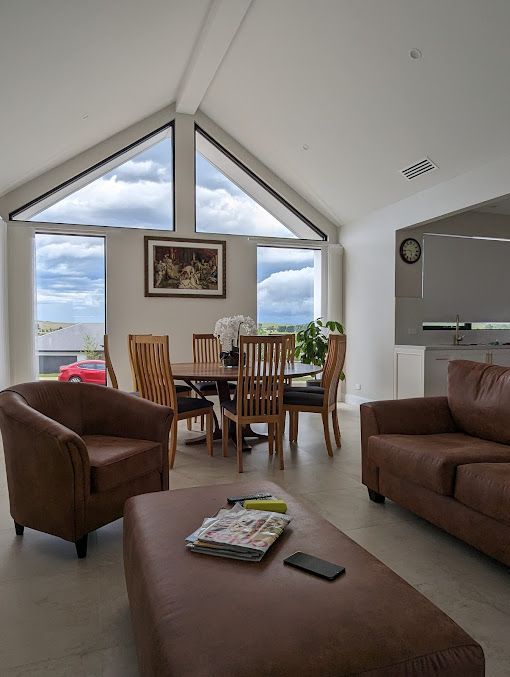A living room with a couch , chairs , table and ottoman. — Thomas Croker Constructions In Myrtleville, NSW