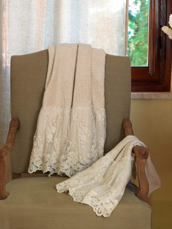 Coperta di pizzo beige drappeggiata su una sedia, vicino a una finestra.