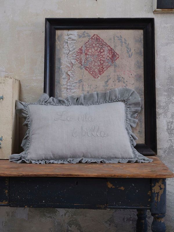 Cuscino con volant su un tavolo davanti a un quadro incorniciato con un motivo a rombi rossi.