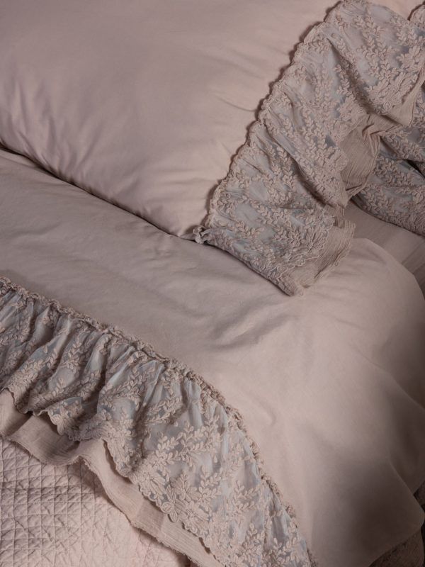 Lenzuola rosa chiaro con rifiniture in pizzo.