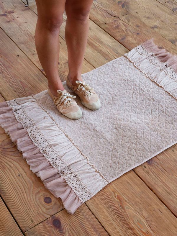 Piedi appoggiati su un tappeto con i bordi arricciati su un pavimento di legno.