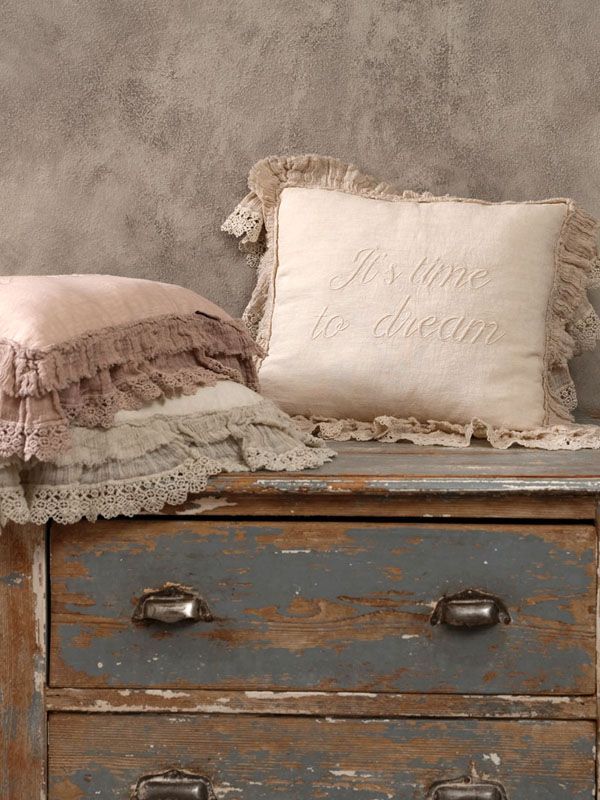 Due cuscini decorativi con bordi in pizzo su un cassetto blu anticato. Su uno c'è la scritta