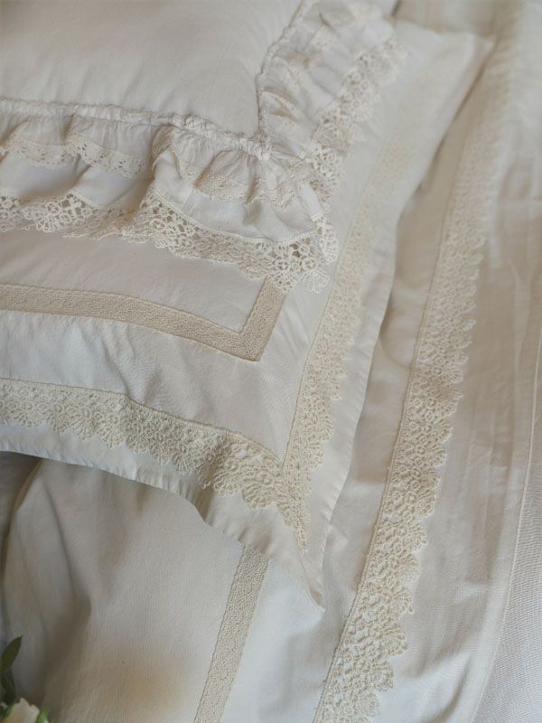 Biancheria da letto bianca con rifiniture in pizzo, comprensiva di cuscino e lenzuolo.