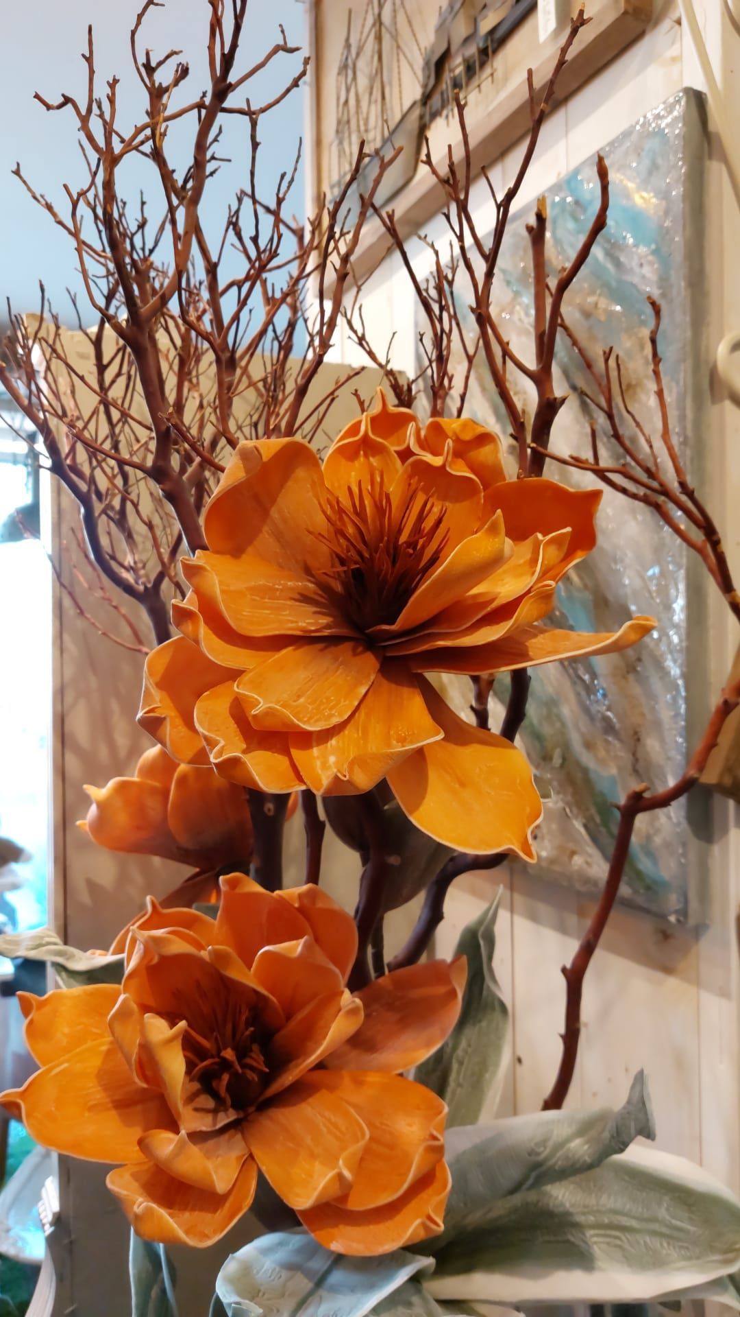 Statuetta di angelo accanto a un vaso decorativo con una rosa blu e un portacandele in argento con una candela blu.