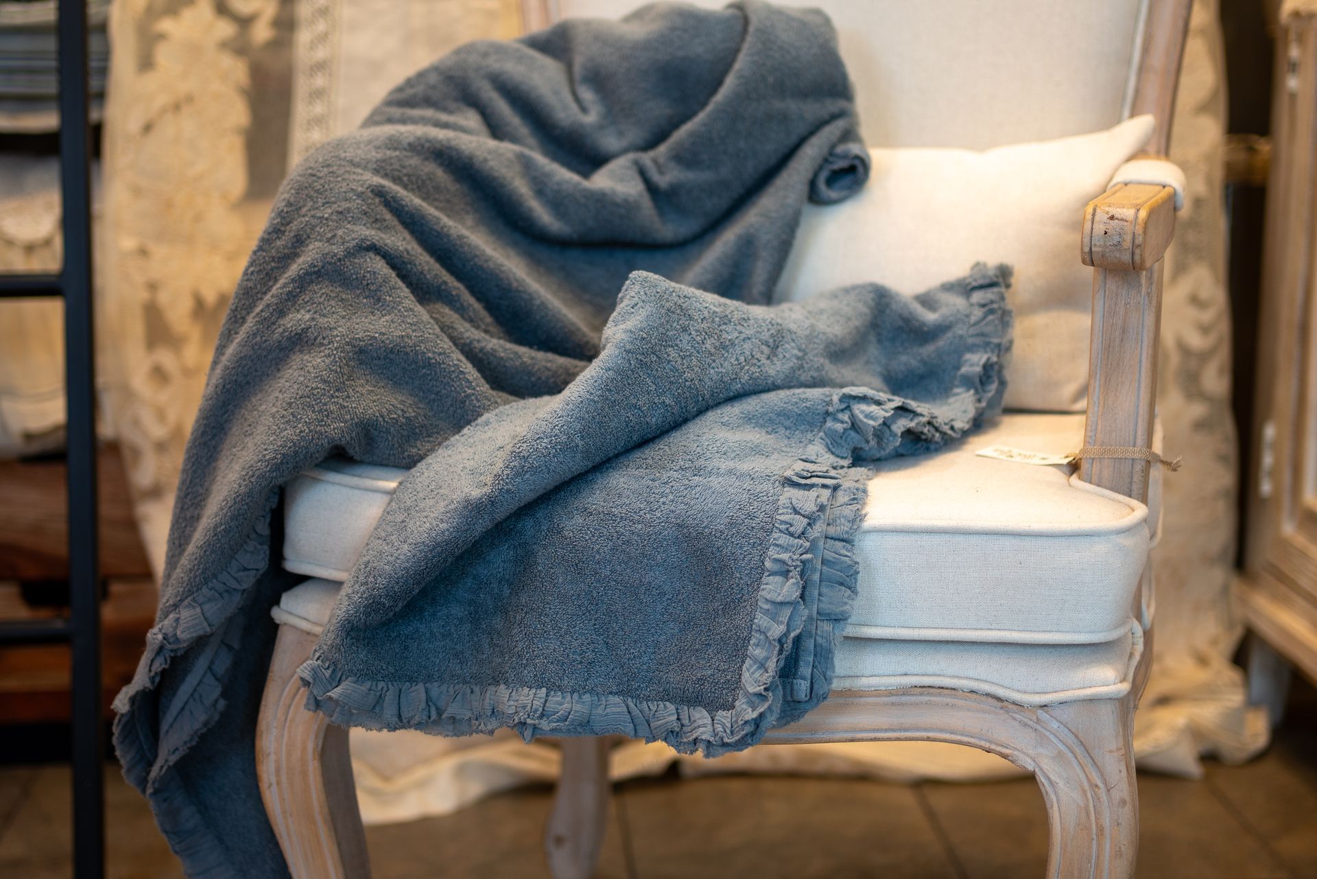 Una coperta blu è stesa su una sedia imbottita bianca con un cuscino.