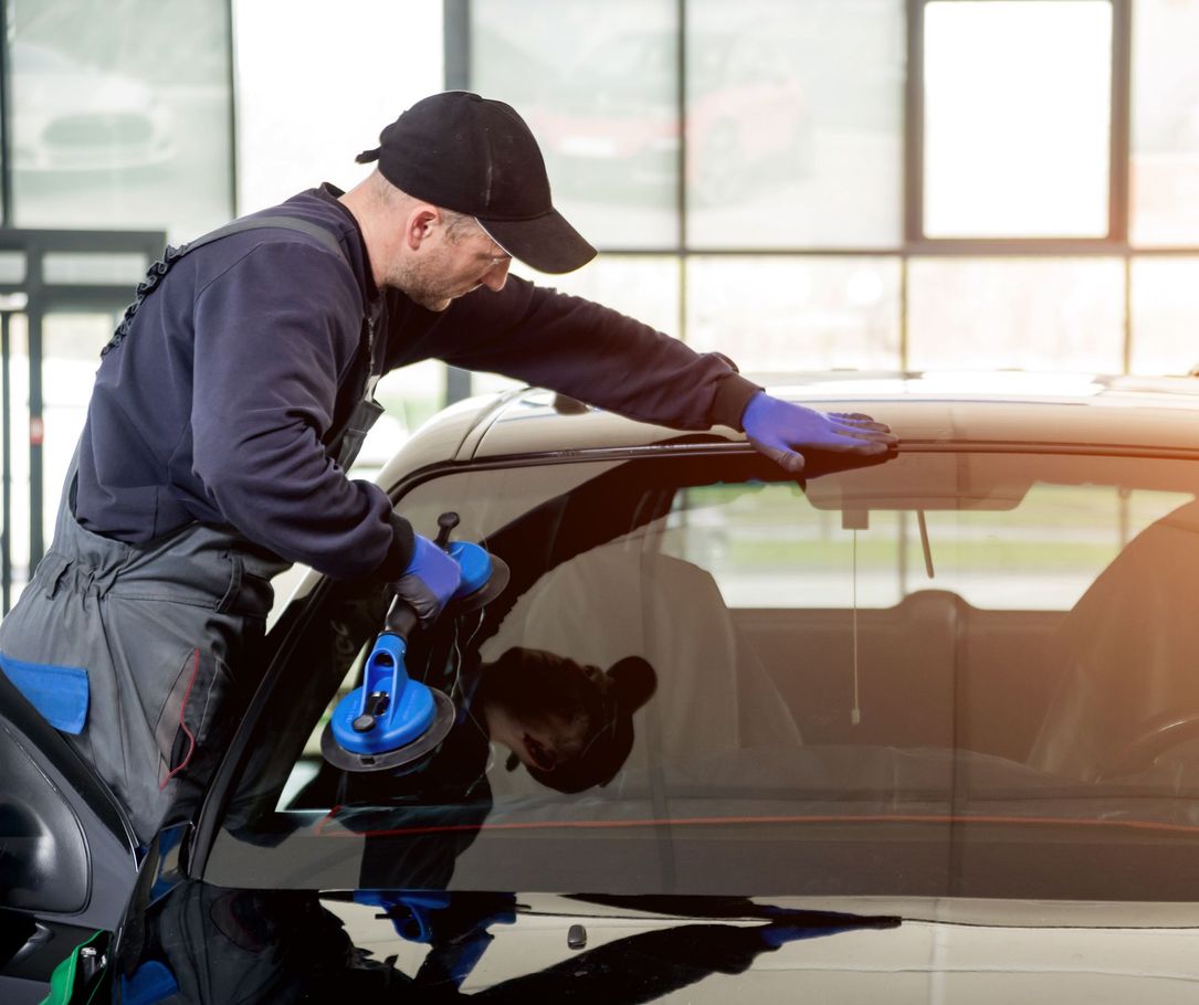 Worker using a blue squeegee to clean the windshield of a black car