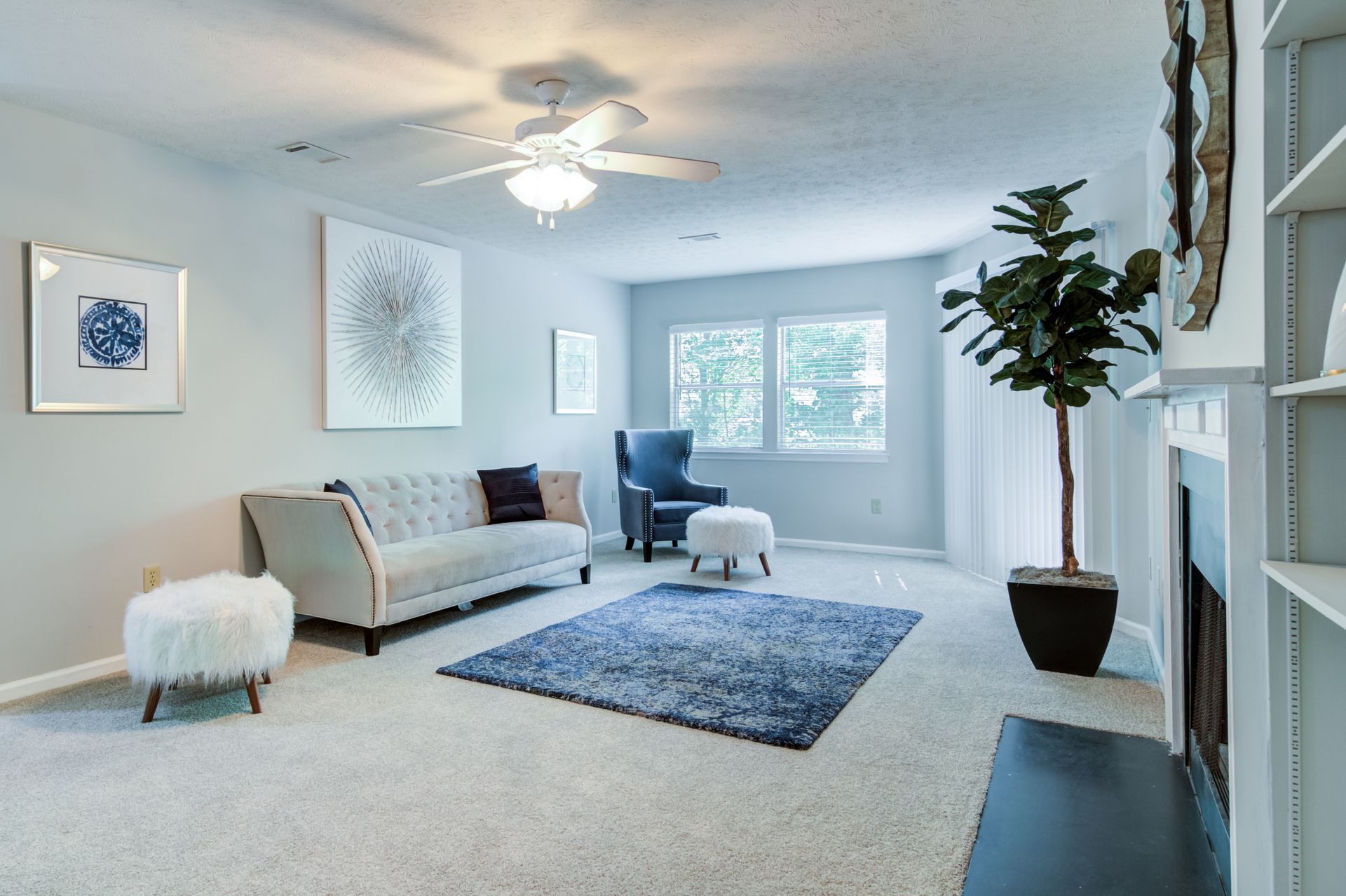 A living room with a couch , ottomans , and a ceiling fan.