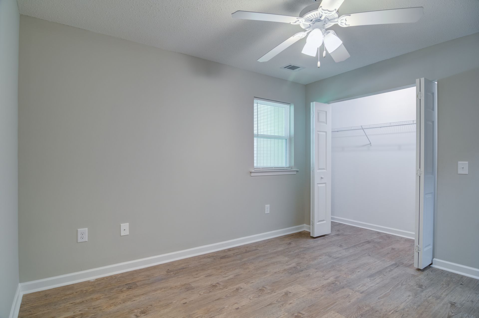 A bedroom with a blue bed and a ceiling fan.