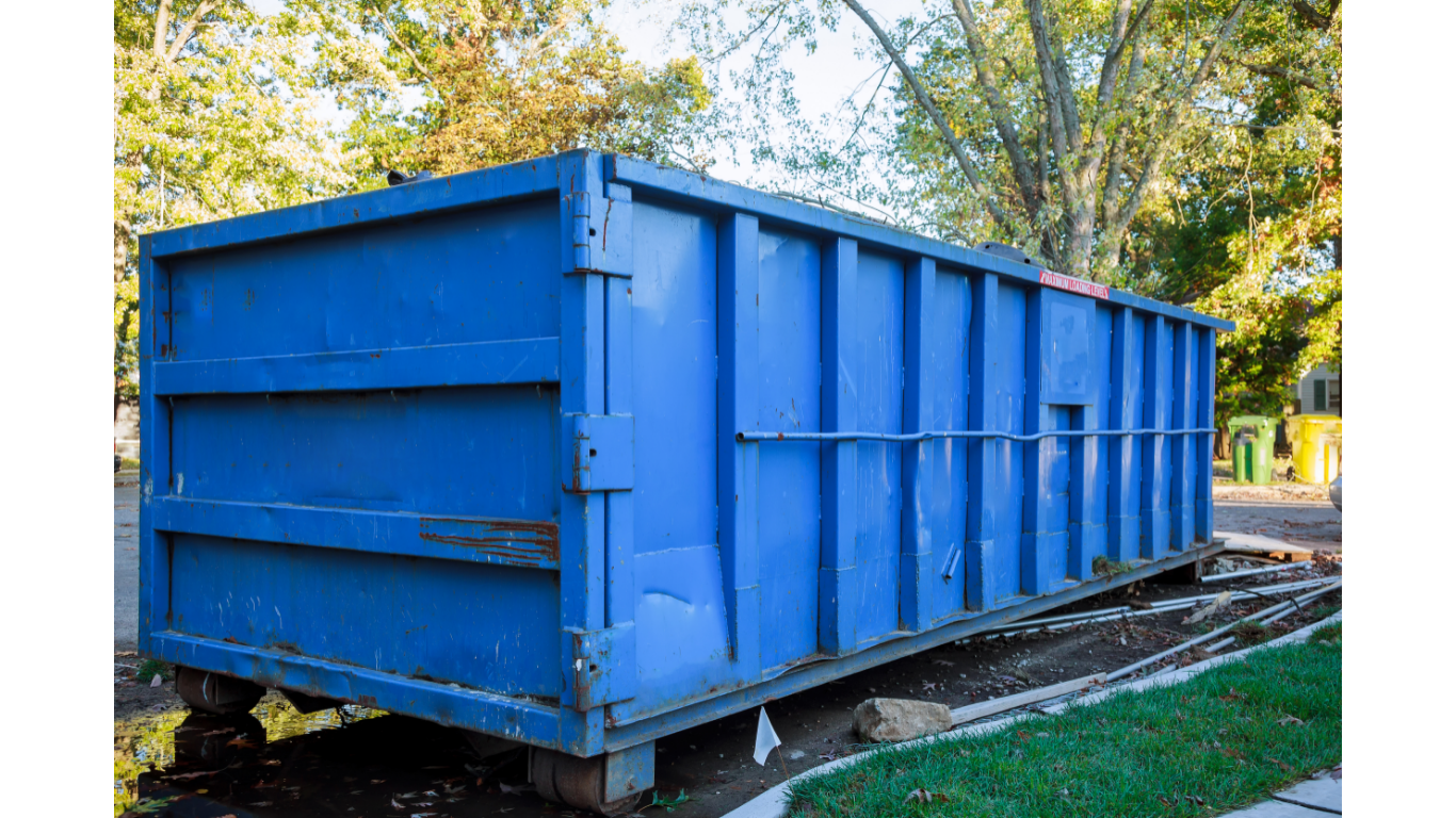 Blue dumpster on wheels outdoors.