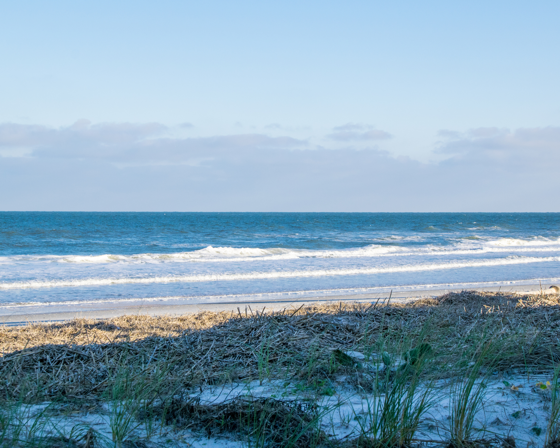 Two young boys in swimwear playing in shallow ocean water at the beach.