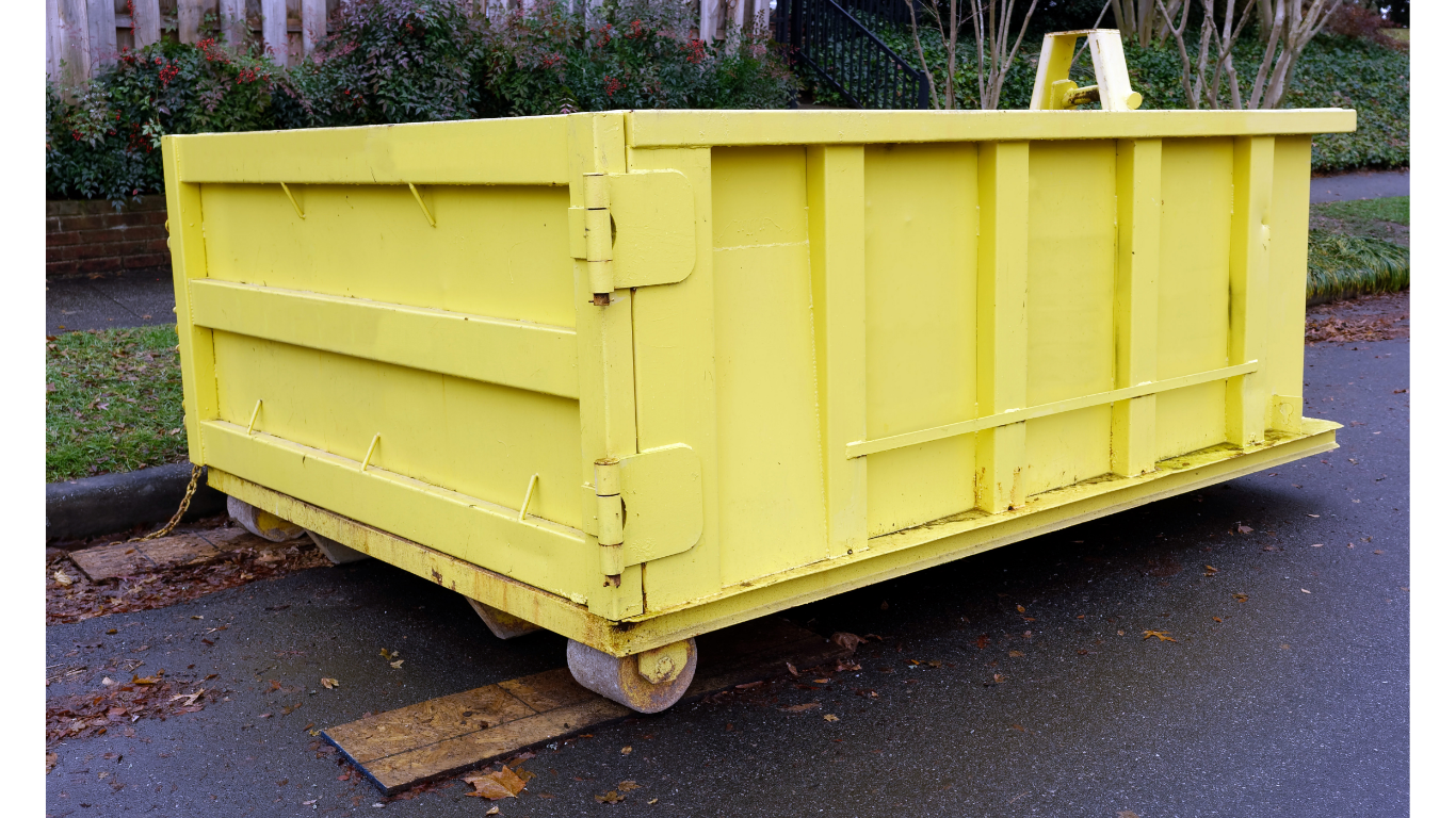 Yellow dumpster on wheels parked on asphalt.