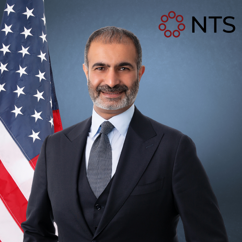 a man in a suit and tie stands in front of an american flag