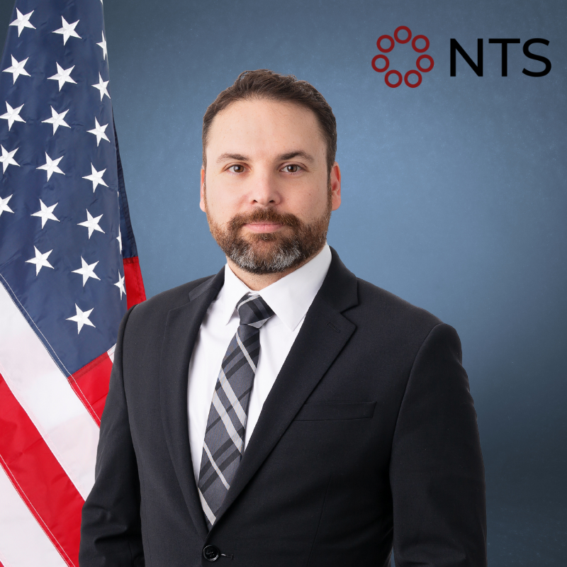 a man in a suit and tie stands in front of an american flag