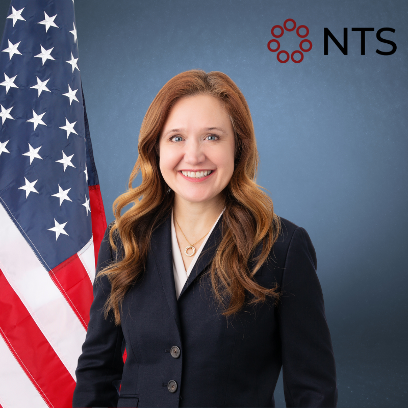 a man in a suit and tie stands in front of an american flag