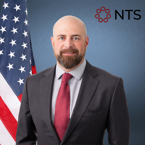 a man in a suit and tie stands in front of an american flag