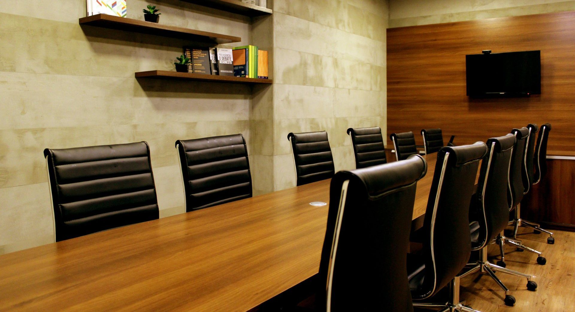 a conference room with a long wooden table and black chairs .