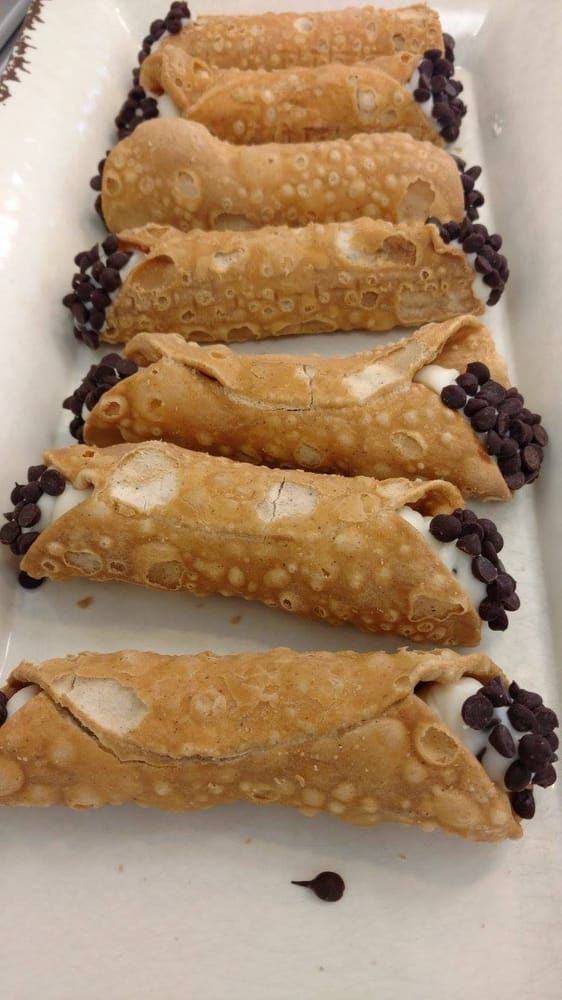 A row of cannoli with chocolate chips on a white plate