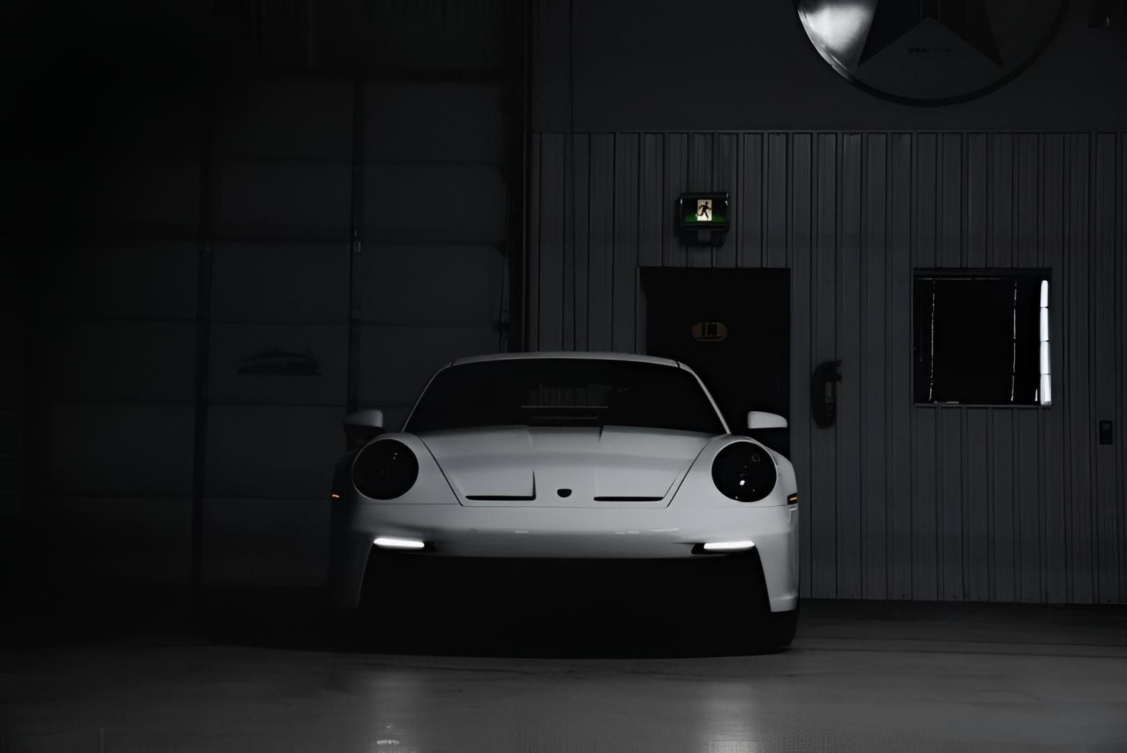 Blue sports car parked in a numbered parking space outside an industrial building with garage doors.