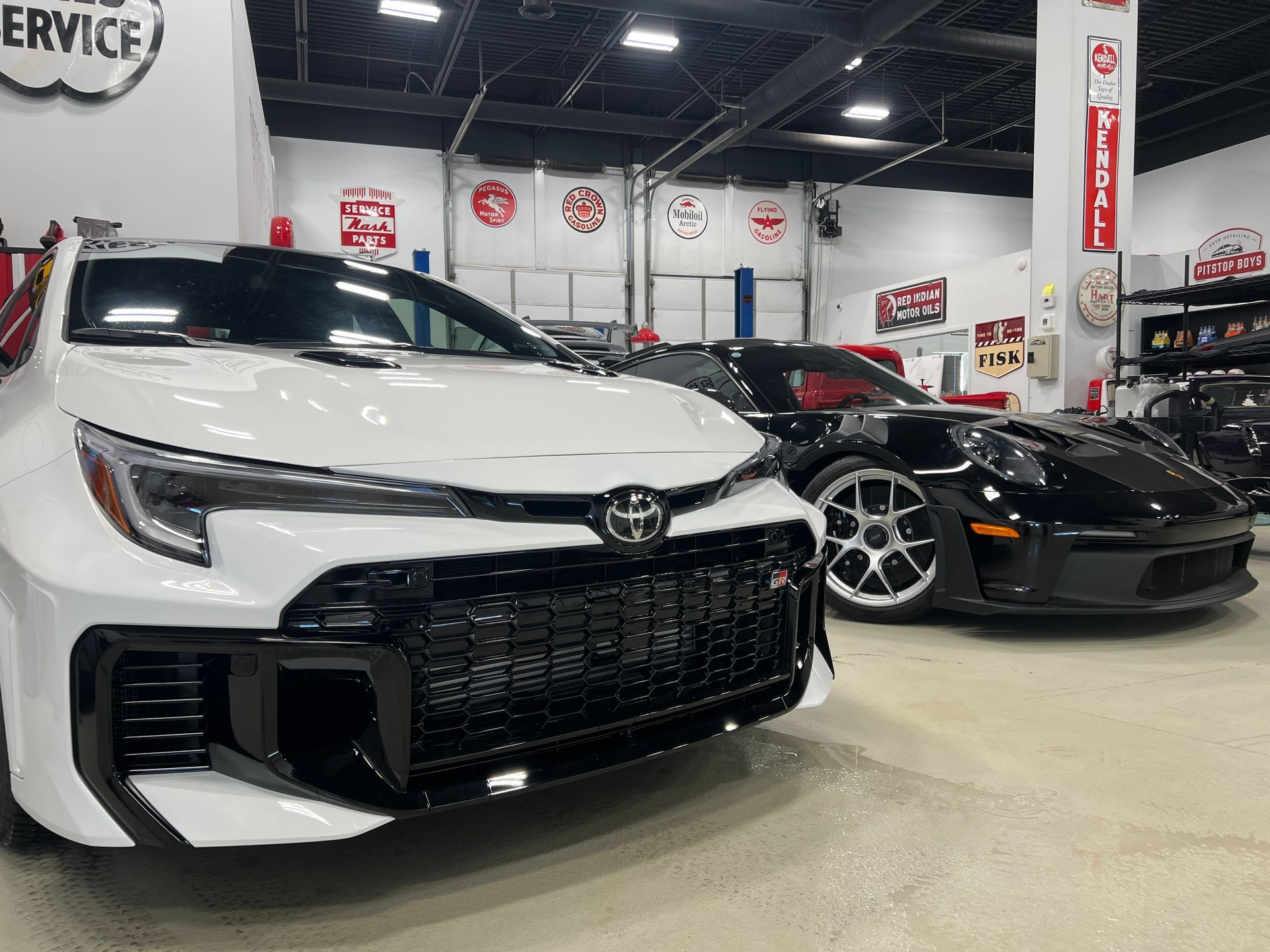 White Toyota sedan and black sports car displayed in a showroom