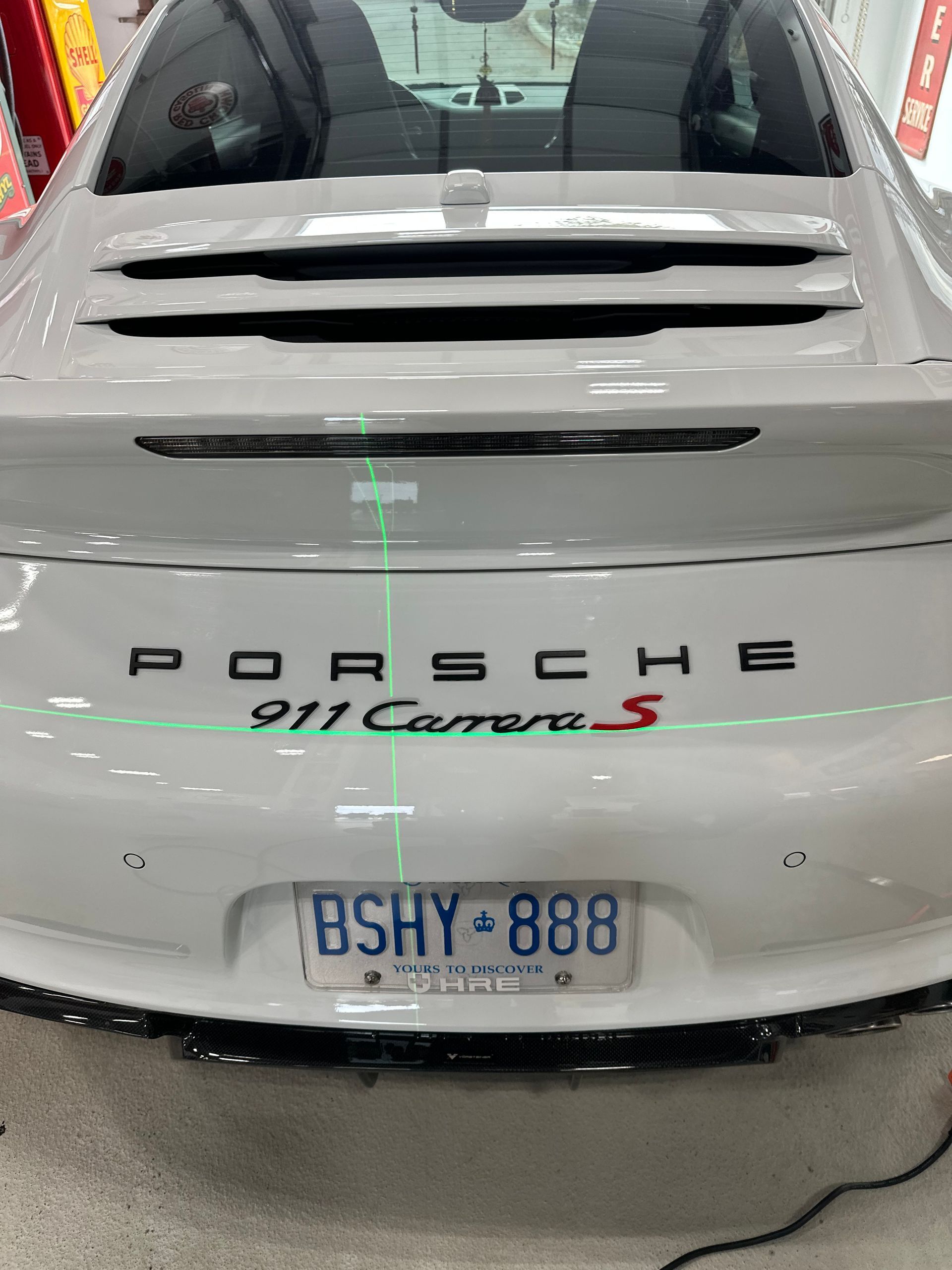 Rear view of a white Porsche 911 Carrera with rear vents and license plate visible.