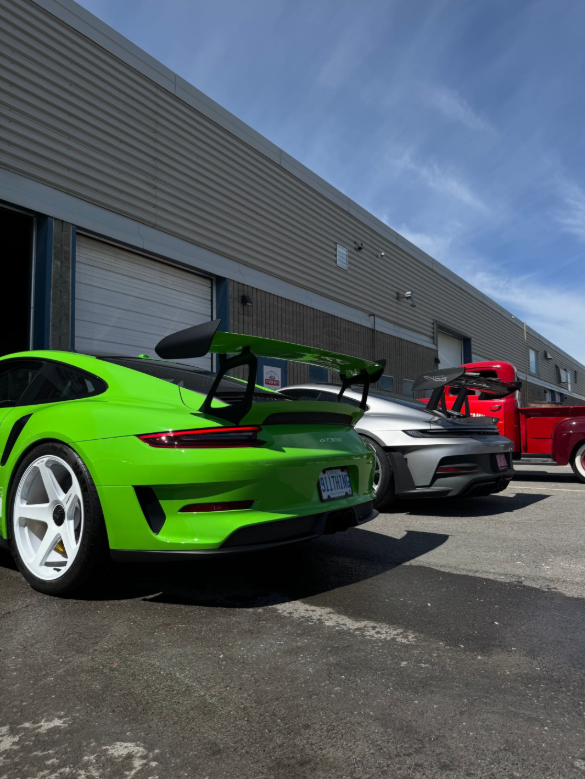 Bright green, gray, and red sports cars parked outside a warehouse building
