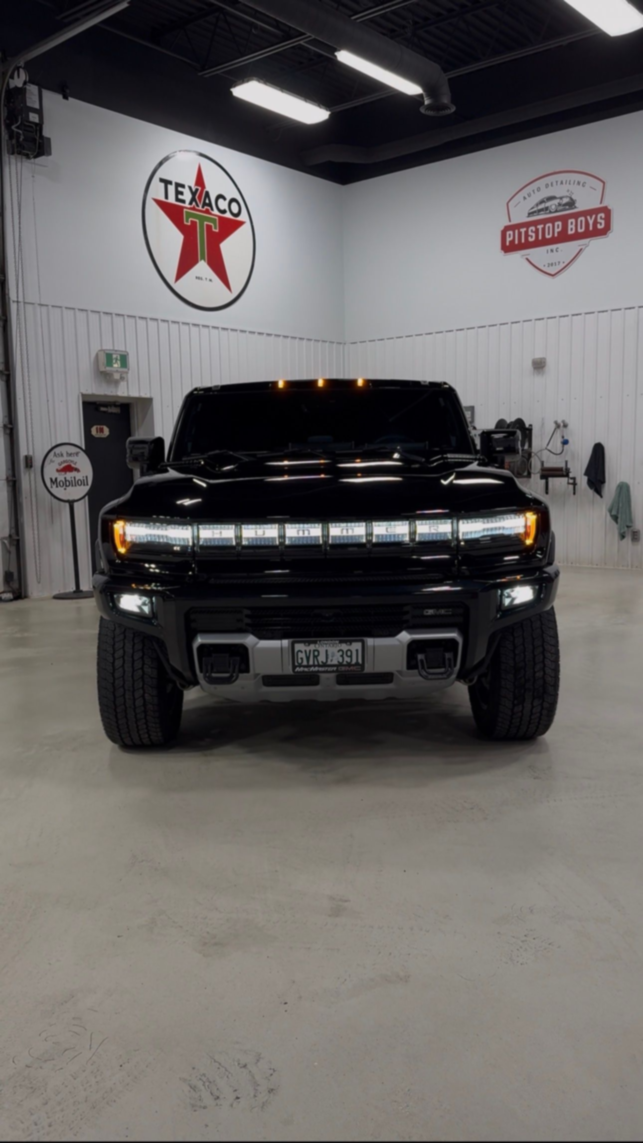Black lifted truck parked indoors under bright lights in a clean garage or showroom.
