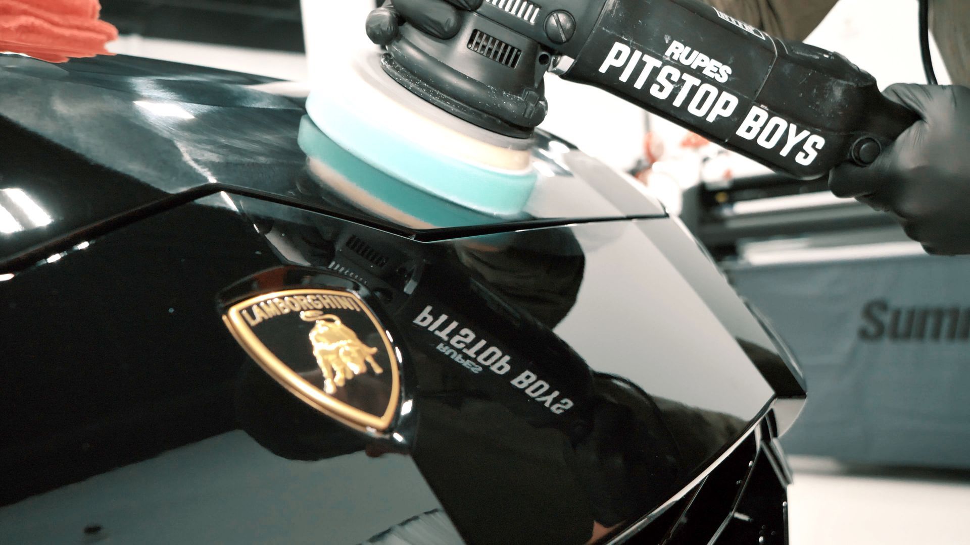 Close-up of a glossy black Lamborghini hood with a Pit Stop Boys polishing tool attached