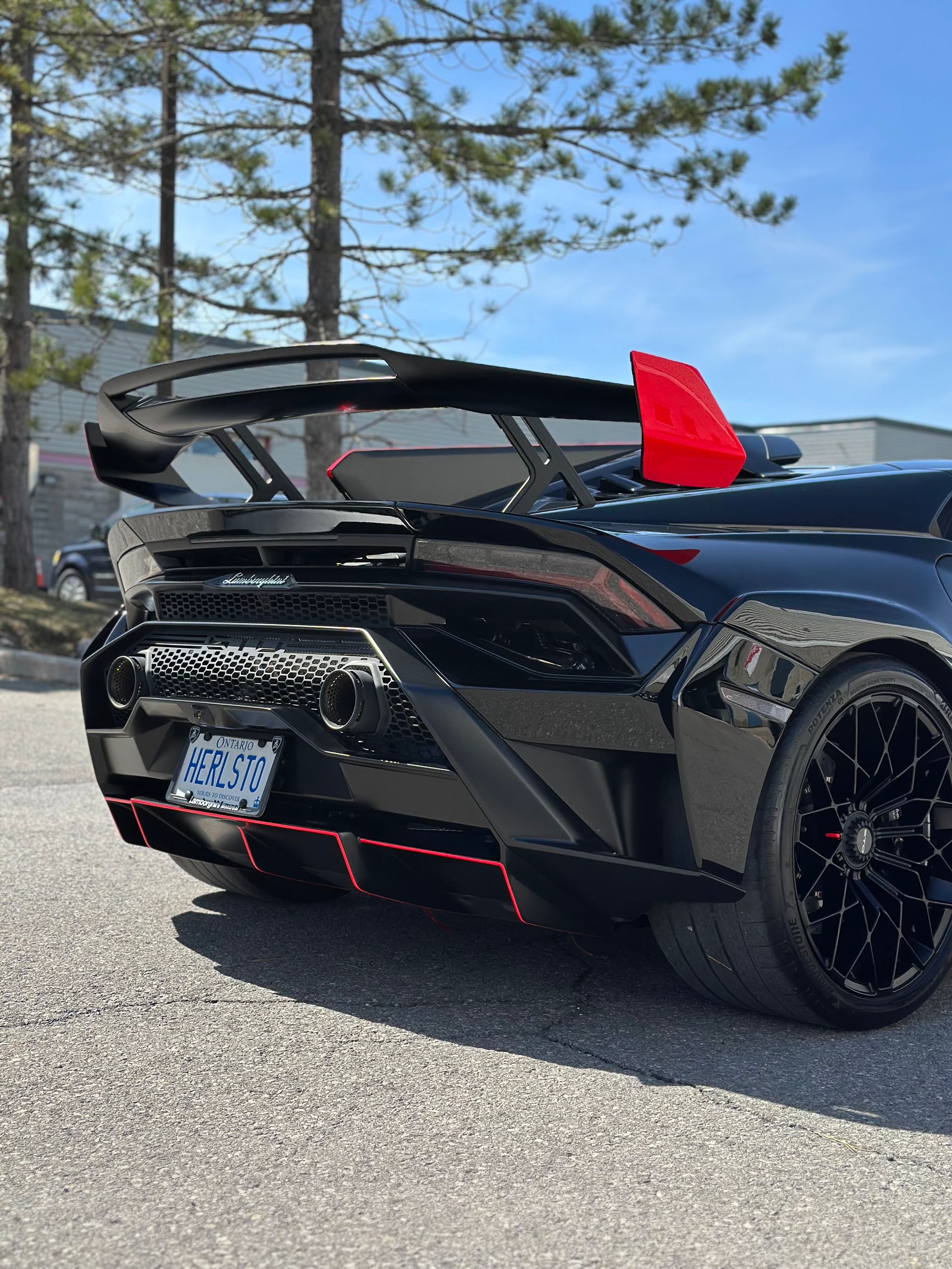 Black sports car with a red roof box parked in a snowy garage or car wash bay