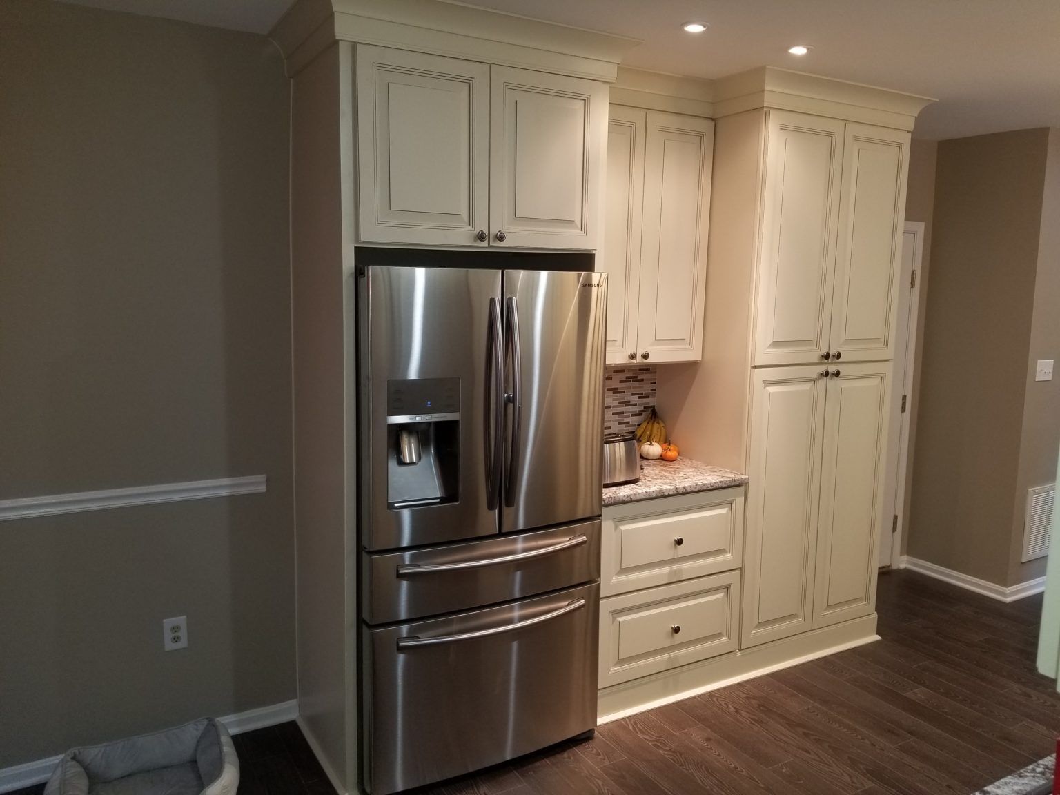 Stainless steel refrigerator with cream-colored kitchen cabinets.