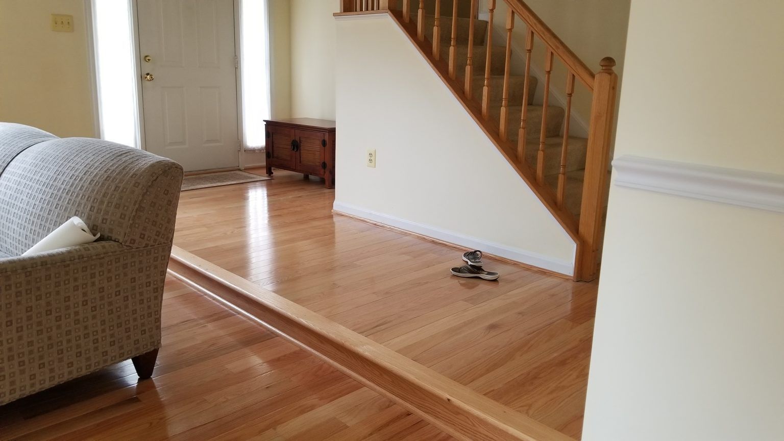 Living room with hardwood floors, stairs, sofa, and front door.