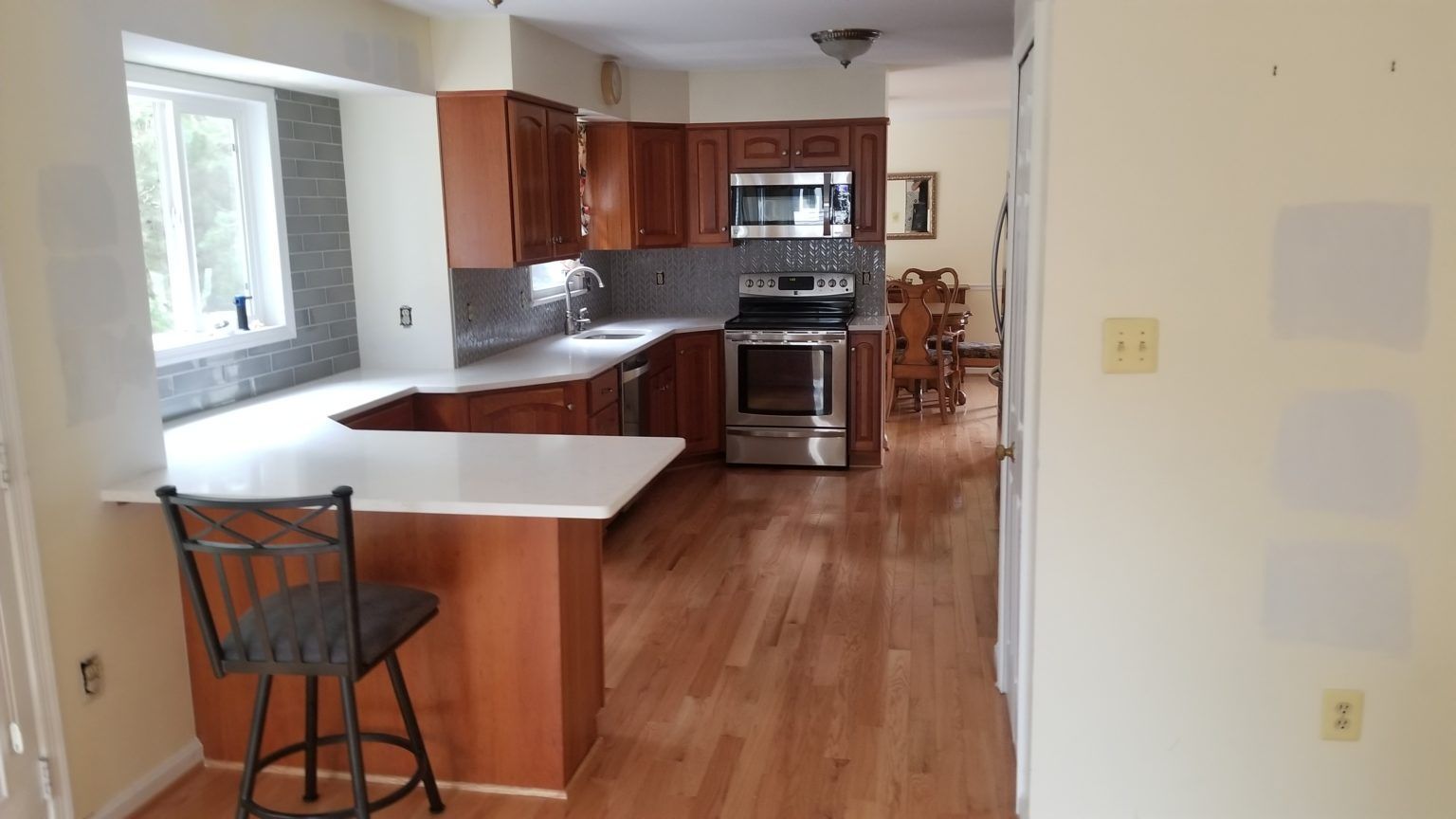 Kitchen with brown cabinets, stainless steel appliances, white countertops, and wood flooring.