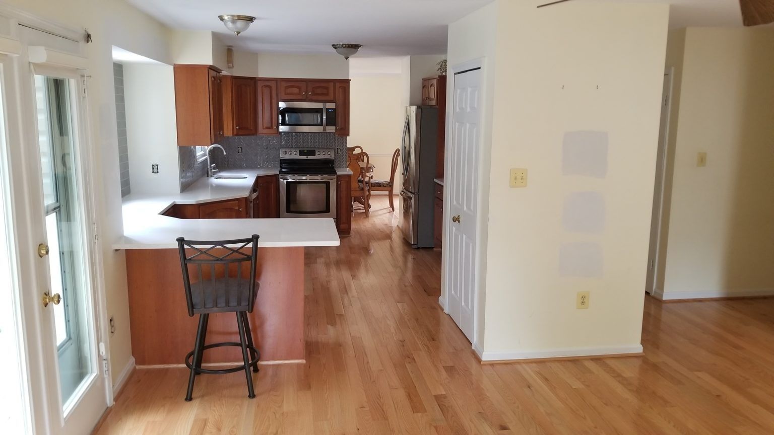 Kitchen with wood floors, dark cabinets, stainless steel appliances, and a breakfast bar.