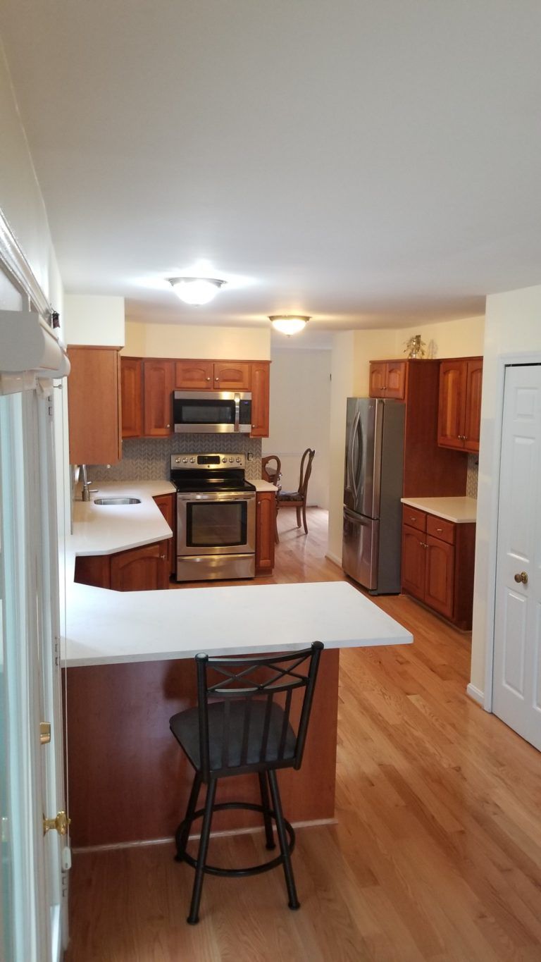 Kitchen with hardwood floors, wooden cabinets, stainless steel appliances, and a breakfast bar.
