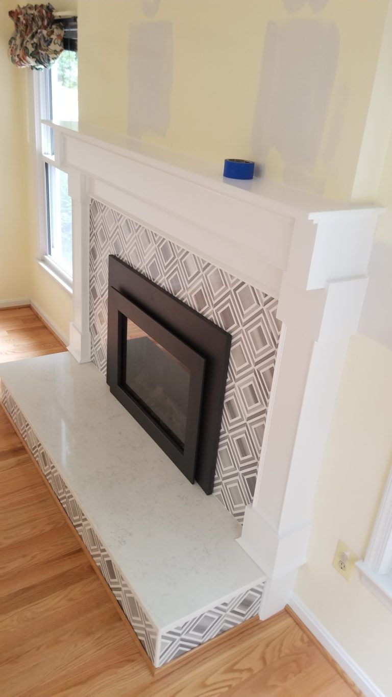 Fireplace with white mantel and hearth, patterned tile surround, and built-in electric firebox.
