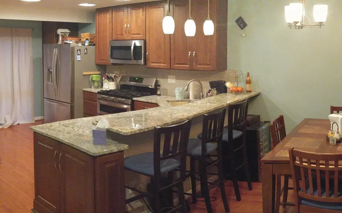 Kitchen with wooden cabinets, stainless steel appliances, granite countertops, and bar seating.