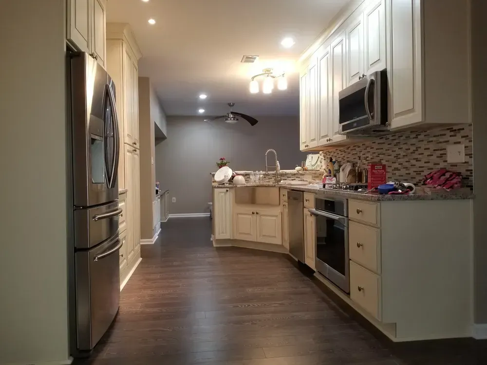 Kitchen with white cabinets, stainless steel appliances, and dark wood floors.
