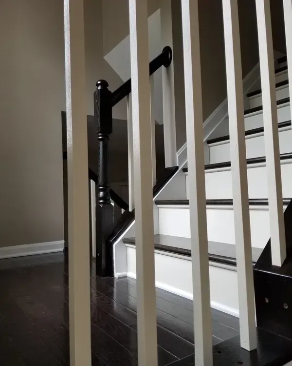 White and black staircase with dark wood flooring and balusters.