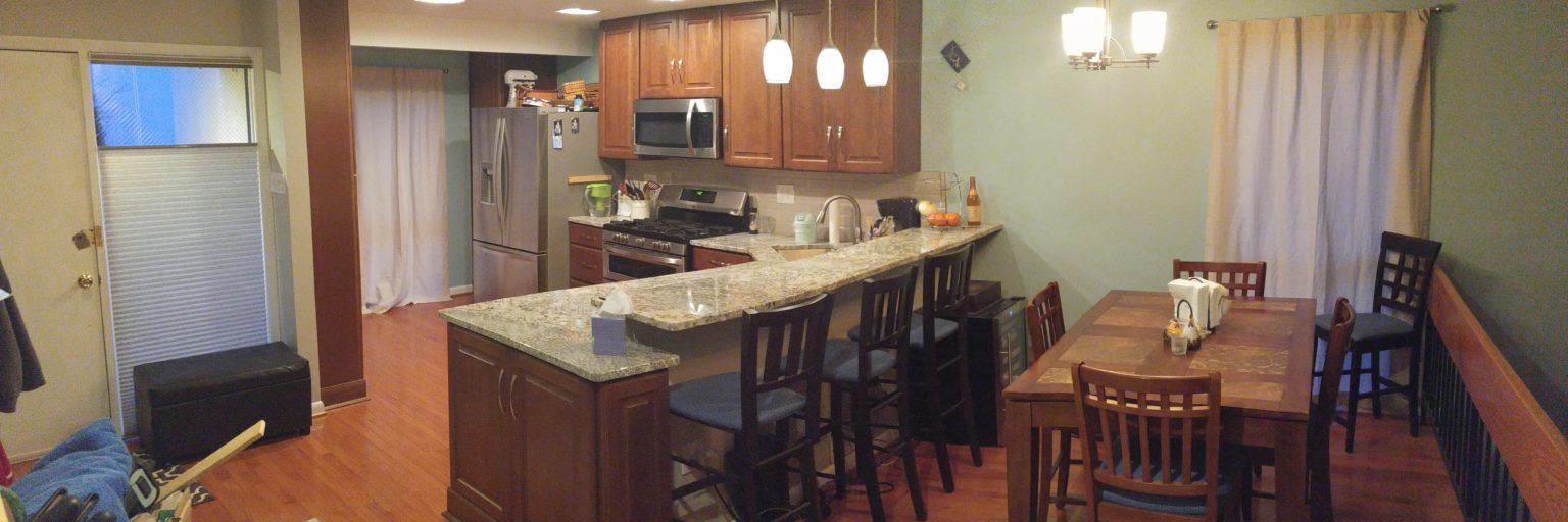 Kitchen and dining area with bar seating, a table, and appliances like a fridge and stove.