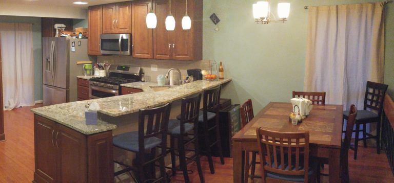 Kitchen and dining area with wooden cabinets, granite countertops, and a wooden table.